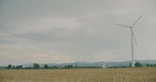 Woman Running On Grass Near Wind Farm