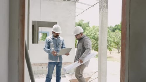 Indian engineer wearing a helmet Standing and inspecting house plans with the foreman. Follow plan i