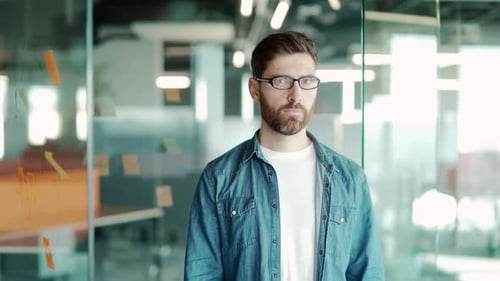 Portrait of a young handsome bearded man. A creative office worker who stands in the modern world