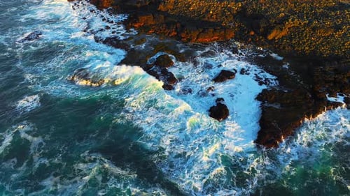 Top Down View on Ocean Waves Crashing and Foaming Around Majestic Rocks and Cliffs Inspiring and