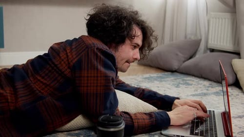 Man Lying on Floor Typing on Laptop