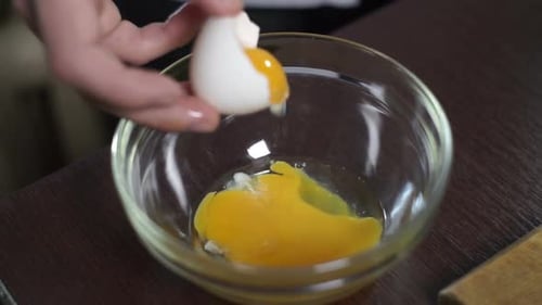 Cracking eggs into a glass bowl for cooking