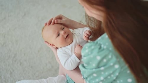 Woman Holds Infant Tenderly Indoors in the Daytime