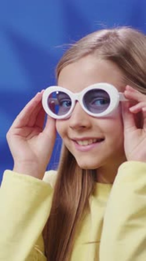 Une fille heureuse portant des lunettes de soleil à la mode vêtue d'une tenue jaune vif souriante
