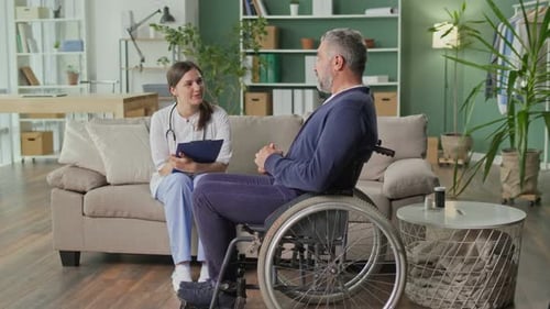 Female Doctor Visiting Adult Man in Wheelchair