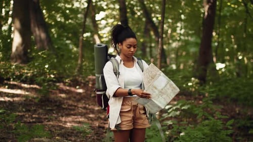 Young African American Woman Reading Map While Hiking in Forest During Daytime
