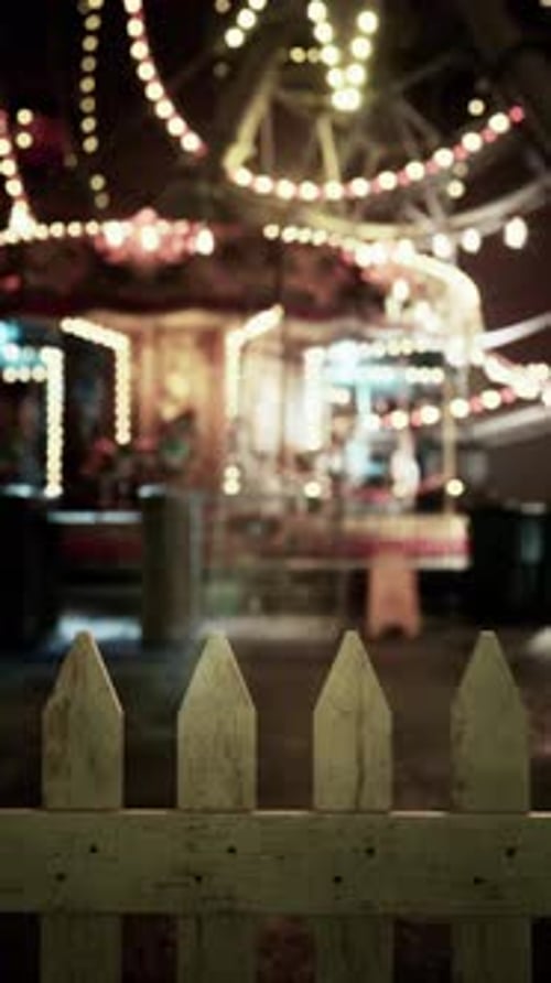 Picket Fence and Blurry Carousel Lights at Night
