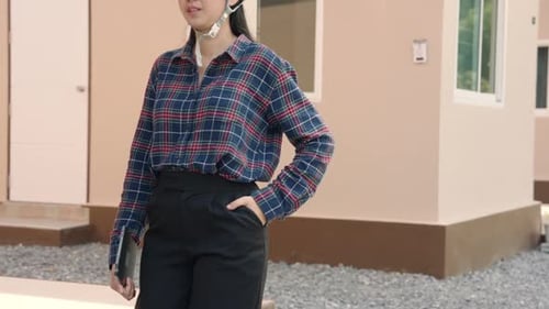 Woman Wearing Hard Hat With Tablet In Front of House