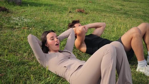 Two Individuals Performing Intense Abdominal Exercises on Green Grass While Focusing on Their