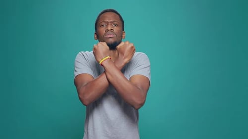 Young Man Shivers, Rubbing Arms in Cold