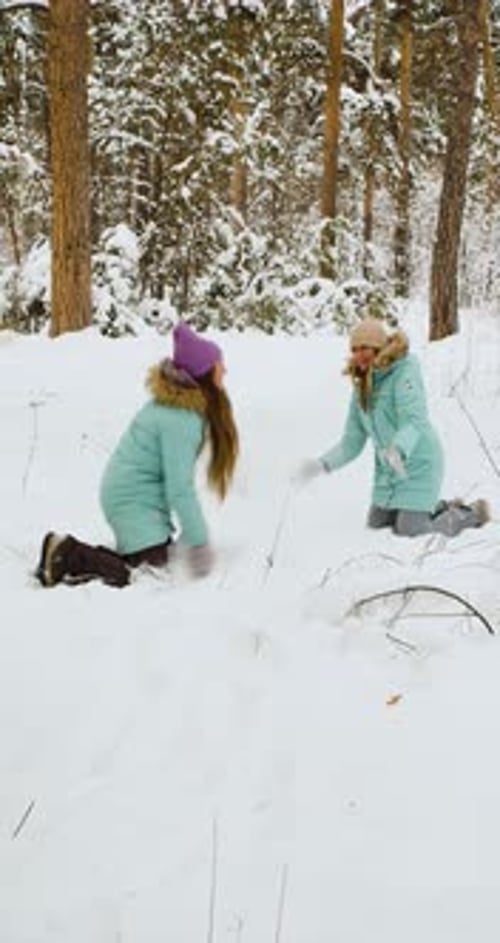 Vertikale Aufnahmen einer jungen Frau, die Spaß in einem verschneiten Wald hat