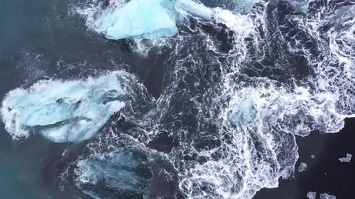 Drone Over Waves Flowing Around Icebergs