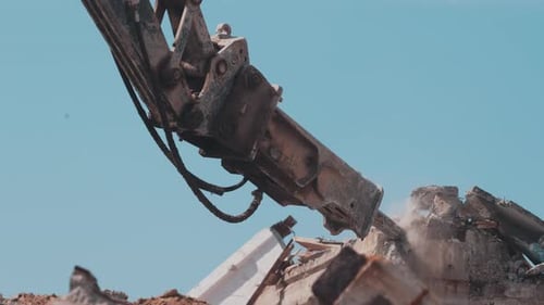 Hydraulic Breaker on Excavator Demolishing Concrete Debris Against Sky