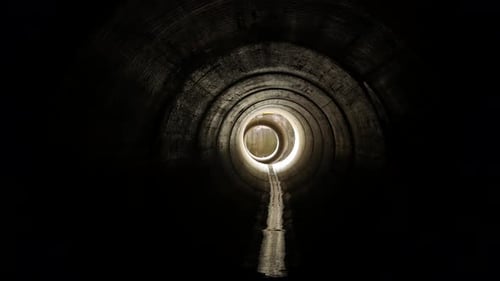 A clip walking towards the light inside a big pipe