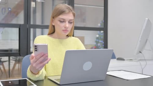 Young Woman Uses Cell Phone and Laptop