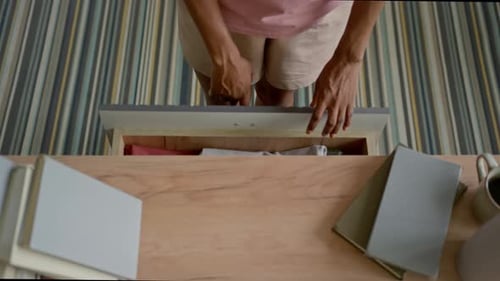 Top View of Young Woman Taking Clothes out of Dresser Drawer