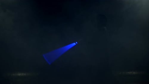 Young Man in Jedi Cosplay Costume with Lightsaber Battle on Black Background in Smoke and Rain Slow