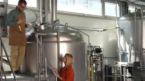 Male brewer explaining the brewing process to a female inspector