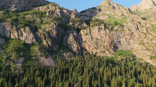 Waterfall Cascading Down Mountainside Into Lush Valley