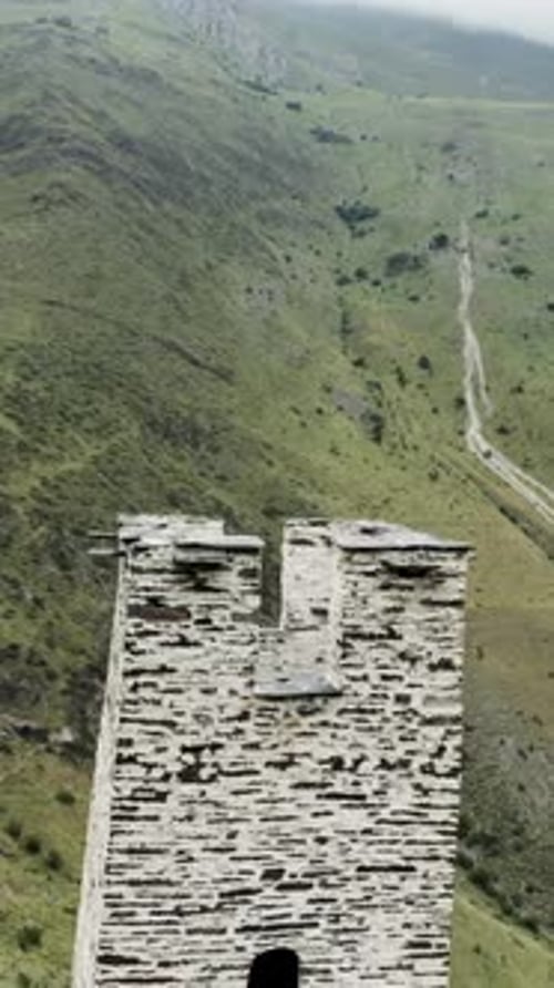 Survol de l'ancienne tour de pierre blanche et de la vallée verdoyante derrière les montagnes verdoyantes de Media et la vieille