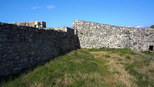 Stone walls of ancient castle surrounding town square, medieval European architecture