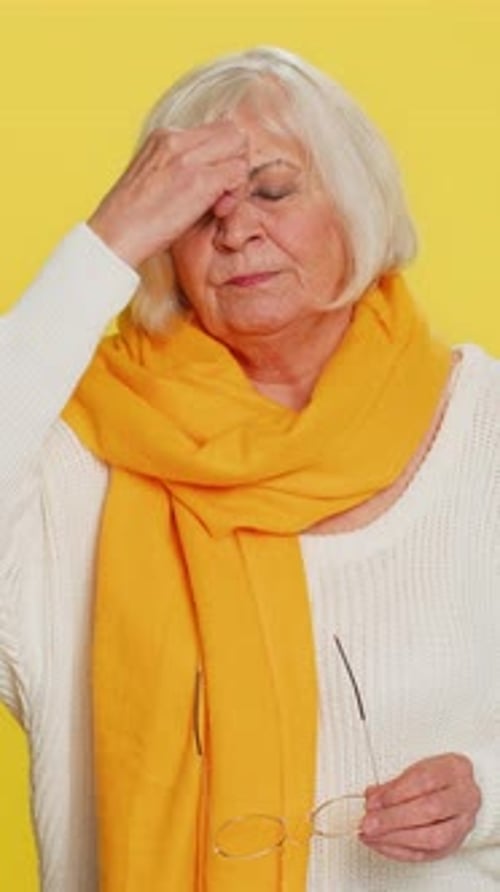 Senior Woman Gesturing No with Finger, Yellow Background