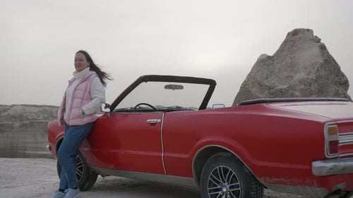 Woman Standing Near Red Cabriolet Retro Car Admiring Mountains in Road Trip