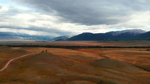 Vast Mountain Valley Landscape Showing Dirt Road and Cloudy Sky Media