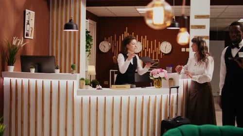 Hotel Receptionist Helping Guest With Tablet