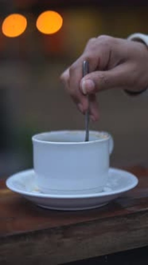 Hand Stirring Coffee in Cup with Spoon
