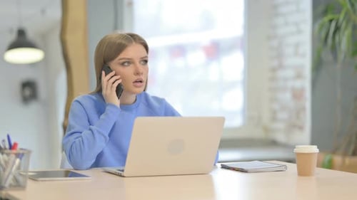 Angry Woman Talks on Cell Phone at Desk