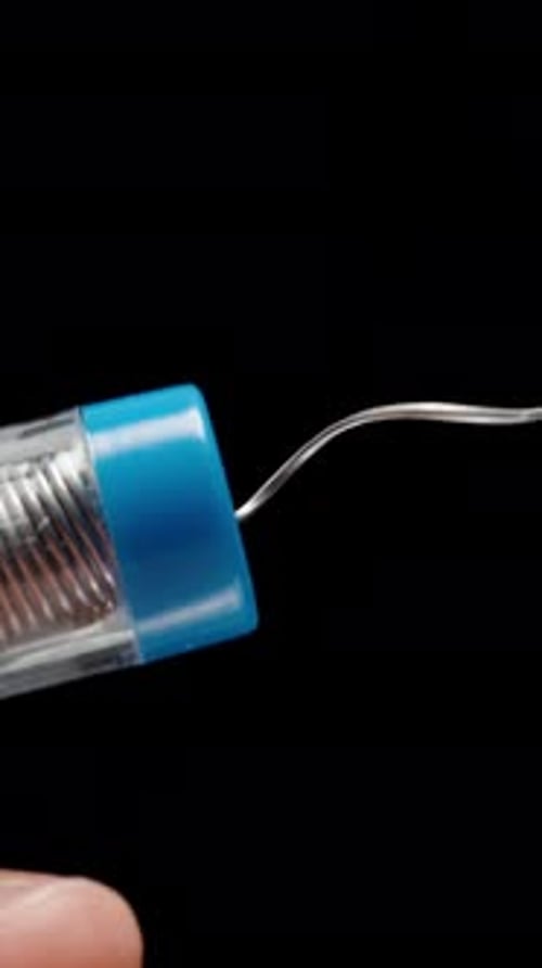 Vertical video. Man's Hands Close-Up Pulling Tin Solder Coiled in Spiral for Soldering Iron from