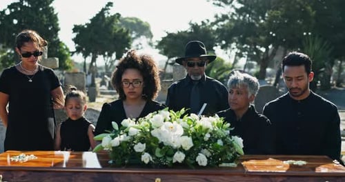 Family, sad and coffin at graveyard for funeral, service and burial ceremony with flower bouquet