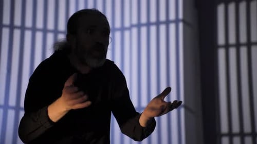 Man Gesturing in Front of Prison Bar Shadows