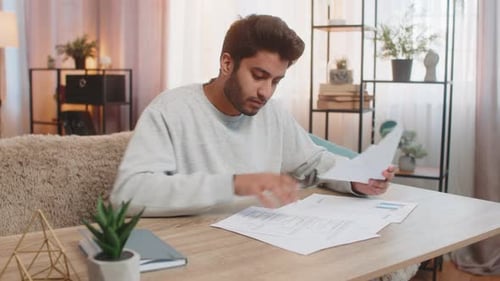 Man Reviews Finances at Home, Looking Concerned