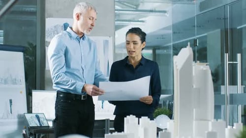 Two Professional Male and Female Architectural Engineers Work with Blueprints, Discussing Building