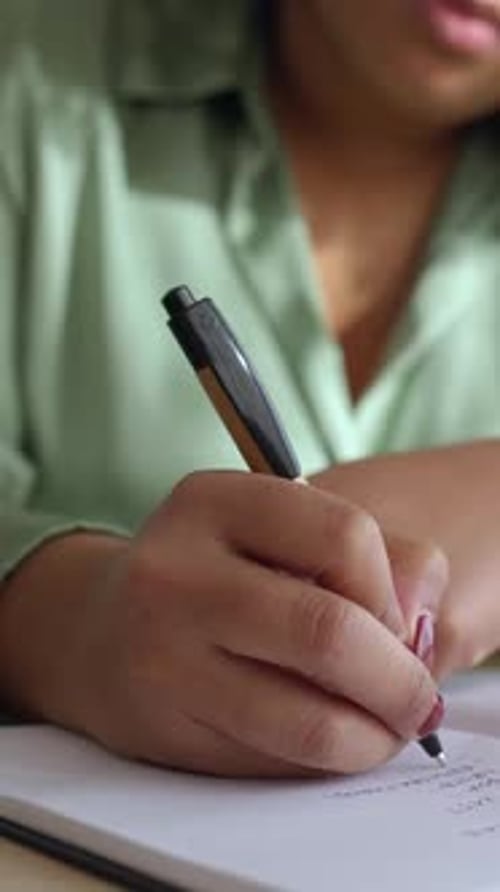 Closeup View of Young Businesswoman Writing on Notebook at Office