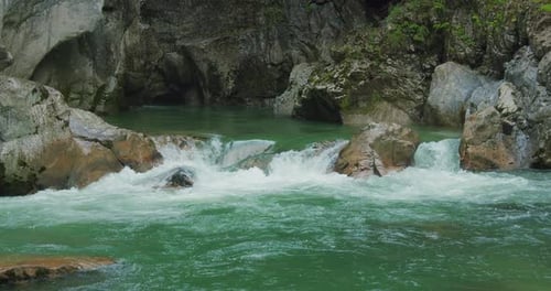 Crystal clear fresh water of mountain river flows among the rocks of a narrow gorge