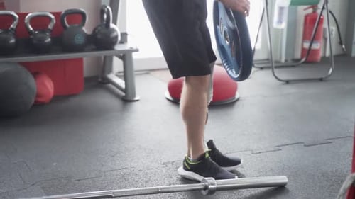 Disabled man with prosthetic leg puts weights for excercise at the gym