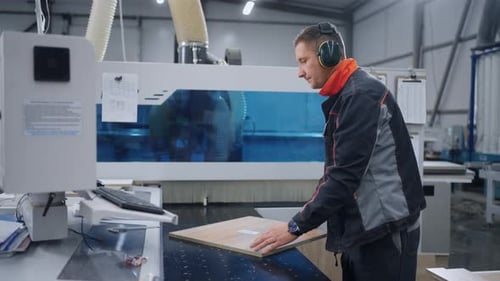Worker Adjusting Computercontrolled Cutting Machine in Woodworking Workshop of Furniture Plant