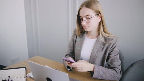 Young Woman Using Smartphone at Desk Indoors