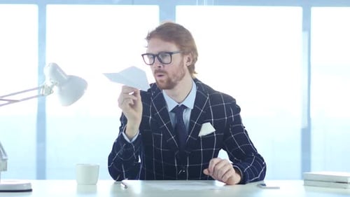 Man in Suit Throws Paper Airplane