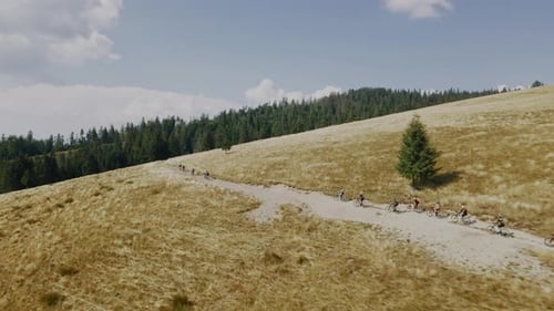 Luftaufnahme einer Gruppe von Menschen, die im Sommer auf dem Berg in der Schlange Elektrofahrräder fahren