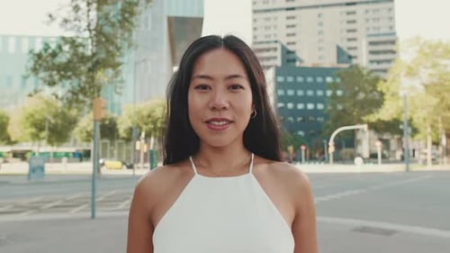 Close up of beautiful smiling young woman looking at camera on modern city background