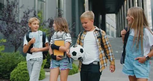 Smiling teenagers boys and girls with school bags, tablet and books walking home after finishing