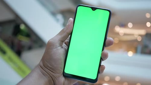 Young Man Hand Using Smart Phone with Green Screen in a Shopping Mall