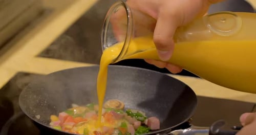 Professional chef cooking delicious omelet on stove in restaurant kitchen