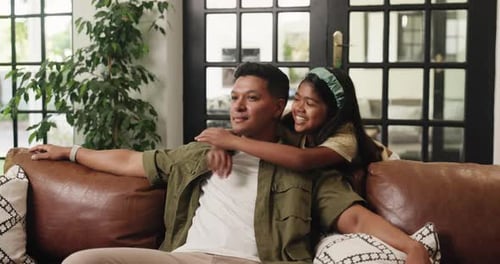 Affectionate Father and Daughter Hugging on Couch Indoors