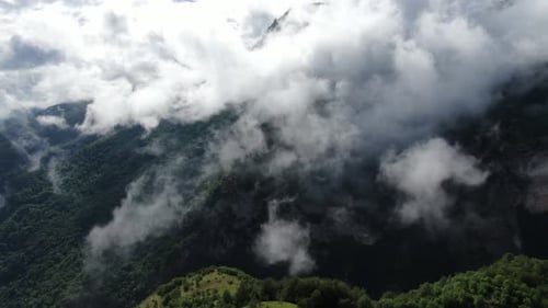 Mountain peaks shrouded in clouds revealing a lush landscape The sky's misty embrace adds depth to