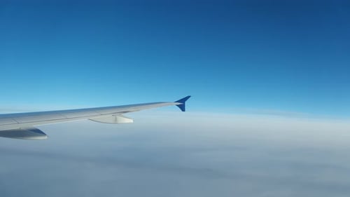 Airplane Wing Soaring Above Cloudscape with Blue Sky